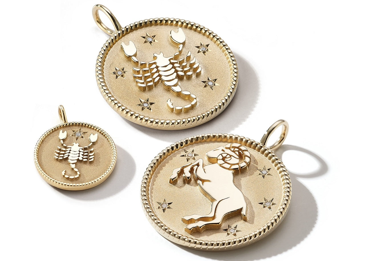Three gold-toned zodiac-themed pendant charms on a white background, including a Scorpion and a Leo design.